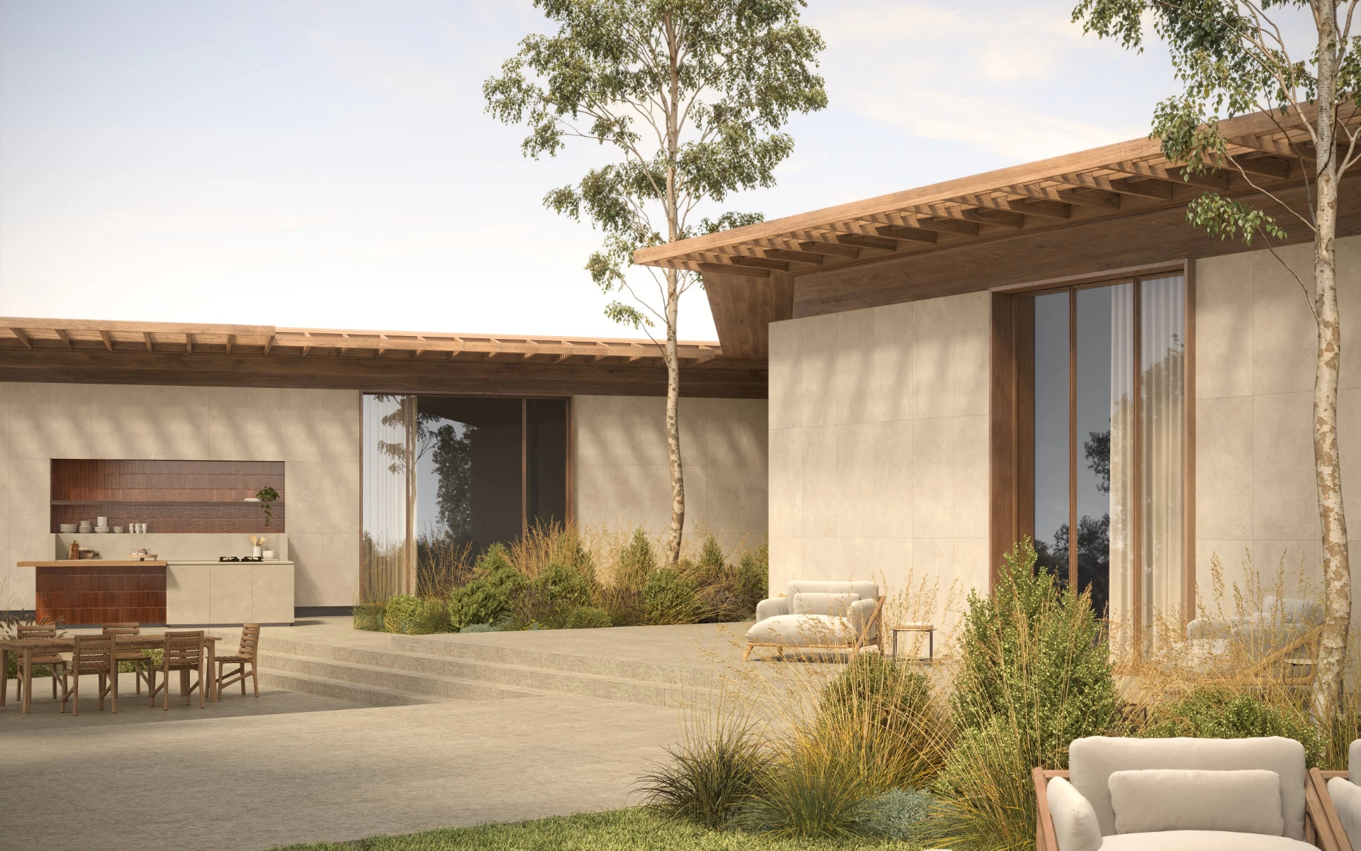 Cucina esterna con piano di lavoro e ante in gres effetto cemento Boost Hux Dune di Atlas Plan, abbinati a toni terracotta.