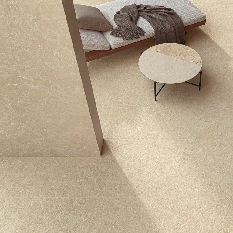 Vista dall'alto del pavimento in Breccia Cream con lettino e tavolino, che mostra la texture brecciata e l'accostamento tra finiture diverse della lastra.