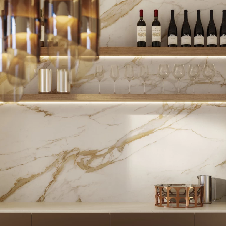 Dettaglio della parete del bar in Calacatta Oro con mensole in legno, dove le ampie venature dorate creano un effetto prezioso e luminoso.