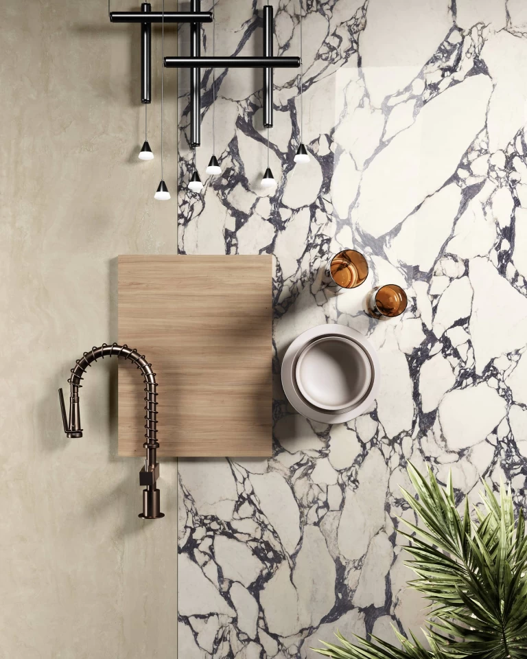 Stilkomposition mit Calacatta Viola Arbeitsplatte, dunkler Armatur, Holzschneidebrettern und dekorativen Accessoires.