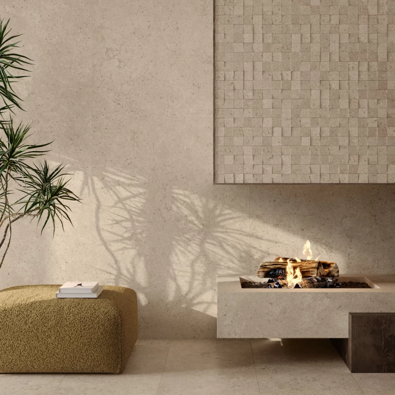 Dettaglio del camino con base e parete in gres porcellanato Nyra Utopia Barley, dove la luce naturale esalta la texture minerale dai toni sabbiosi.