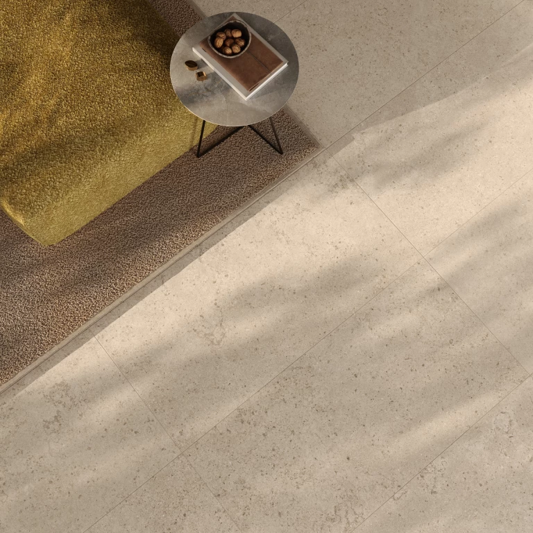 Dettaglio di living con pavimento e pareti in gres effetto pietra Nyra Utopia Barley di Atlas Plan.
