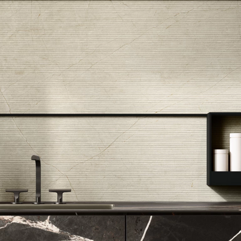 Dettaglio di cucina moderna con top e ante in gres effetto marmo Sahara Dark, abbinati a un rivestimento a parete dai toni avorio.