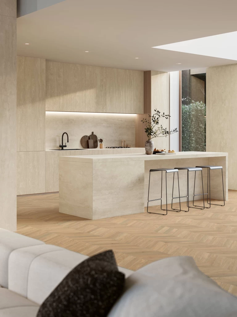 Side view of the open-plan kitchen with island and Travertino Navona White countertop, paired with light wooden flooring for a bright, elegant atmosphere.
