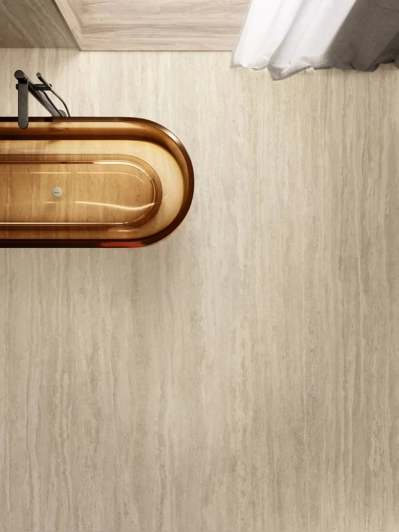 Top view of the freestanding bronze-finish bathtub set on a Travertino Romano Sand porcelain stoneware floor.