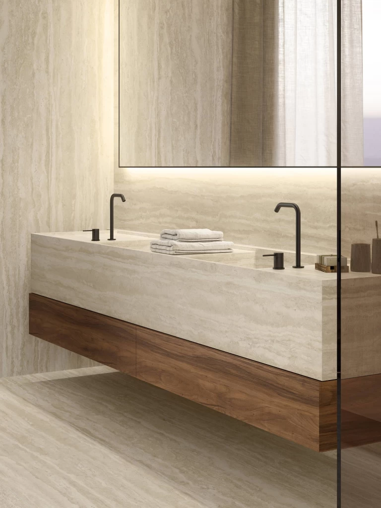 Close-up of the suspended basin in Travertino Romano Sand stoneware with wooden accents and matt black modern taps.
