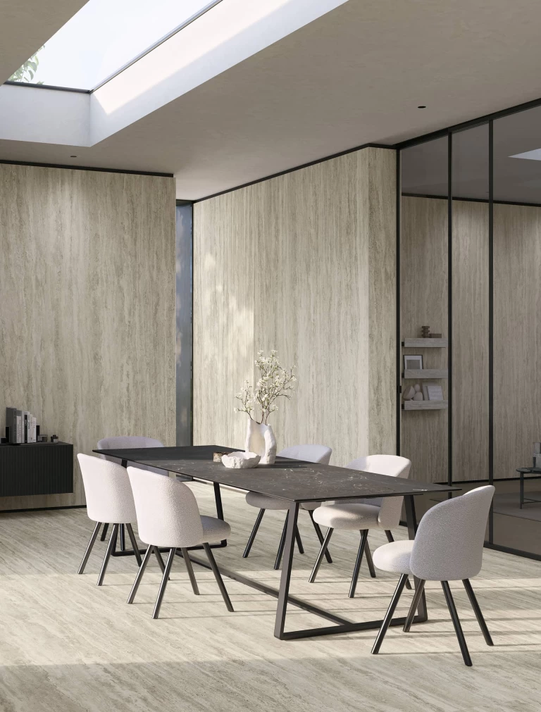 Elegant dining area featuring floor and walls in Travertino Romano Silver with a minimalist black table.