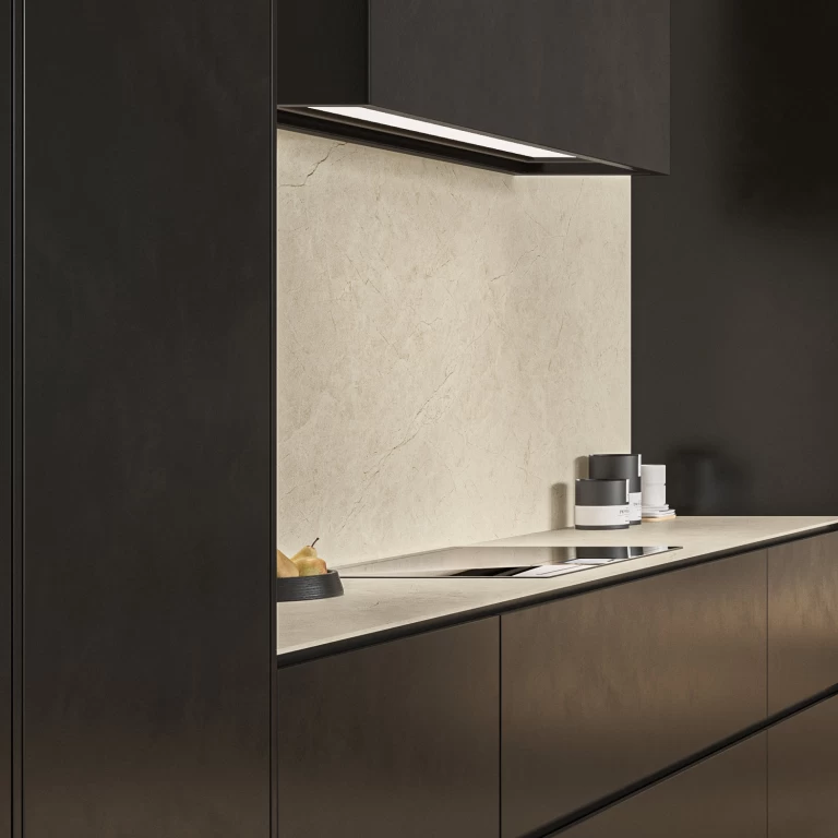 Cooking area backsplash in Vanilla White marble-effect porcelain, framed by dark cabinets and lit by the ceiling-mounted hood.