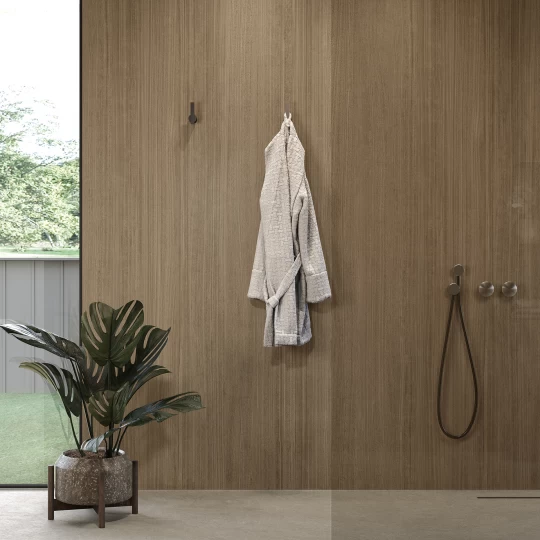 pared baño con gres efecto madera Atlas Plan con planta y toalla en el fondo