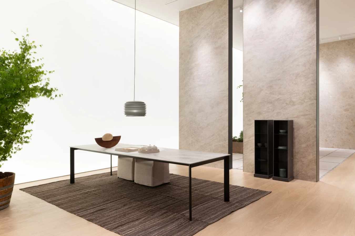 Dining table with Atlas Plan large slab top in a minimalist living space with stone-effect walls