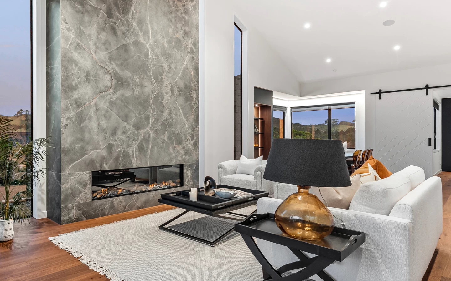 Living area with fireplace in Atlas Plan Fior di Bosco marble-effect porcelain and white sofa