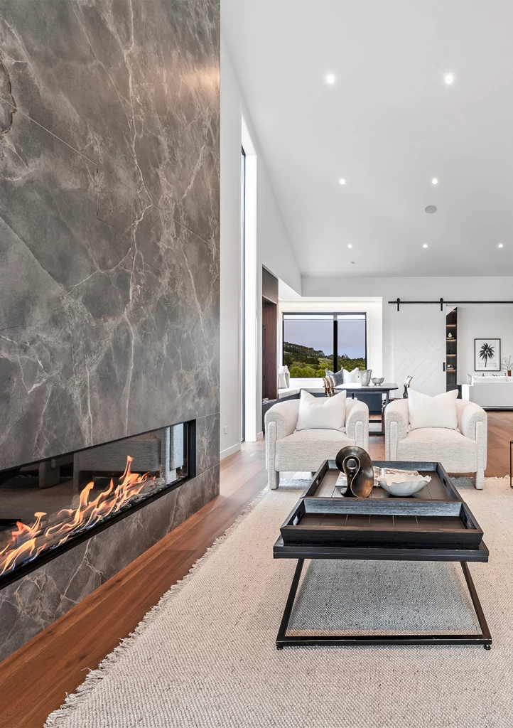 Fireplace in Atlas Plan Fior di Bosco marble-effect porcelain and bouclé armchairs in the living area