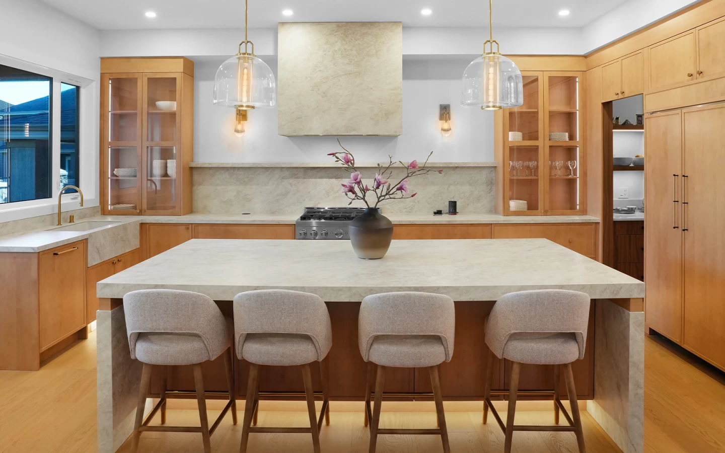 Vue de face de l'élégante cuisine avec îlot central et revêtements en grès cérame Taj Mahal - Atlas Plan