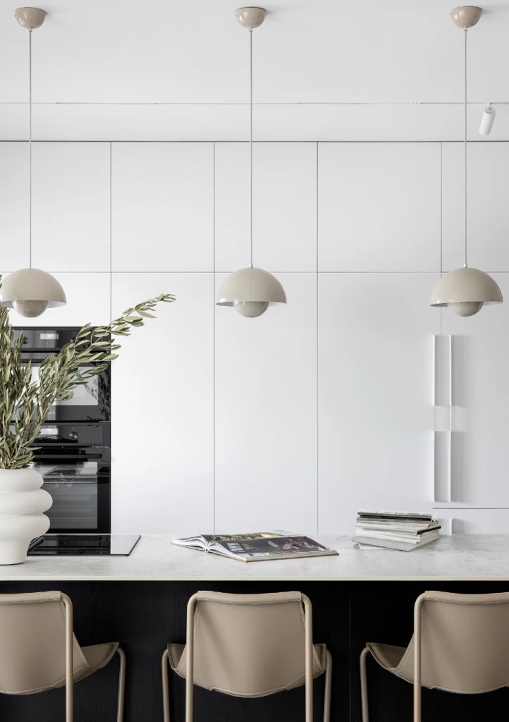Weitwinkelaufnahme eines Wohnbereichs mit offener Küche, deren Marmoroptik Crystal White von Atlas Plan mit dem klaren und modernen Raumdesign verschmilzt