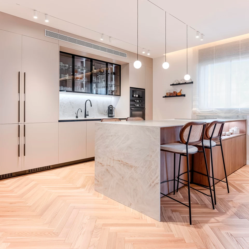 An elegant kitchen with an island, countertop, backsplash and sink clad in Atlas Plan's Crystal White, lending brightness and sophistication to the room.