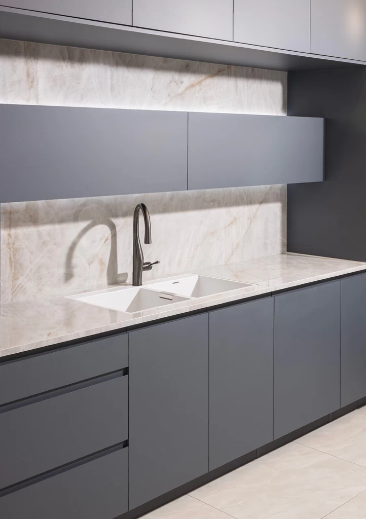 Close-up of an Atlas Plan Crystal White porcelain kitchen countertop paired with dark brown glass vases and a modern kitchen in the background