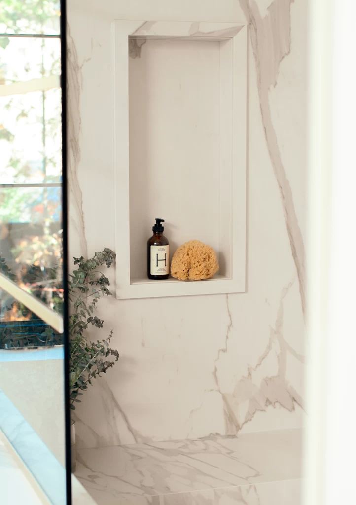 Ниша в ванной комнате, облицованная Calacatta Bernini, с непрерывной текстурой и светом